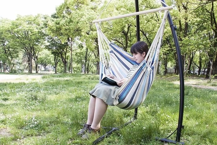 ハンモックに座って本を読んでいる女性の写真
