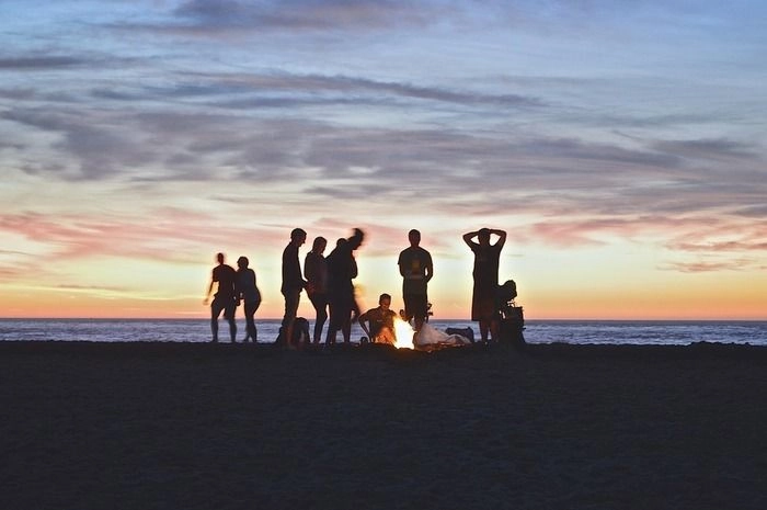夕暮れの海に焚き火をしている青年達