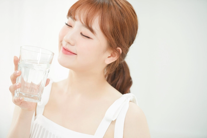 グラスに入った水を飲む女性