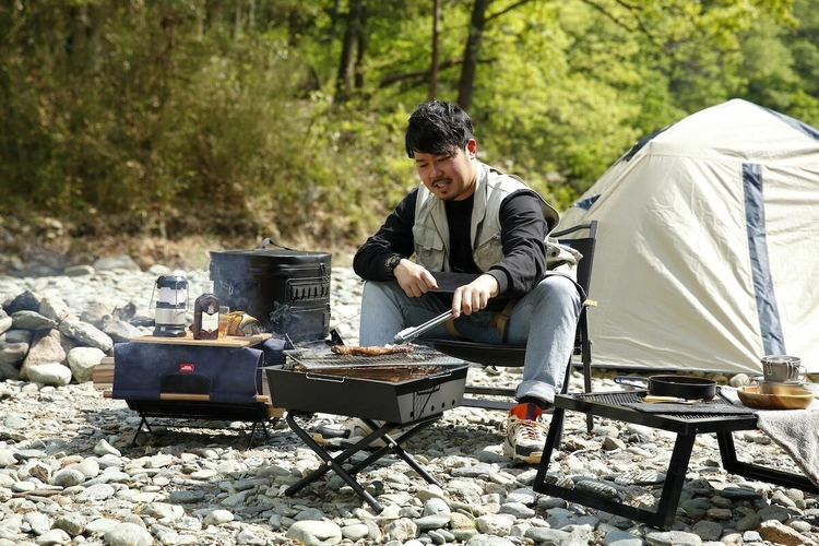 焚き火台で肉を焼く男性