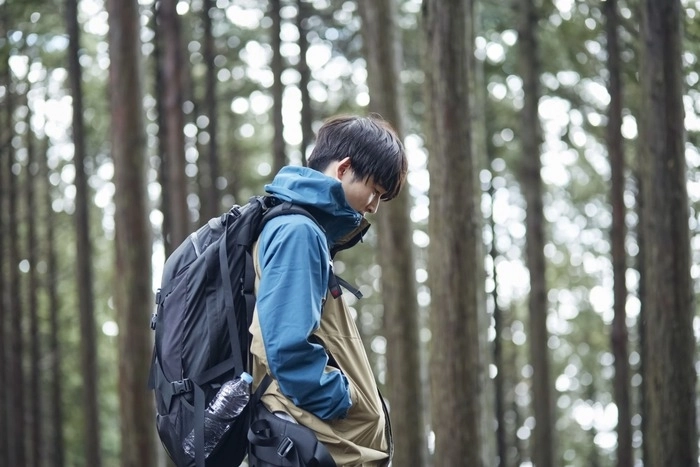 おしゃれなアウターを着て登山をしている男性の画像