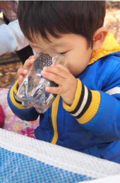 手作りコップで手作り経口補水液を試飲する子供