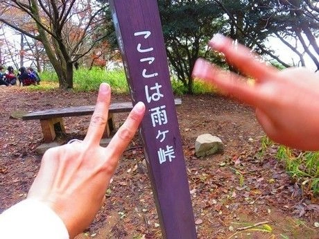 ここは雨ヶ峠と書かれた標識とピースサイン