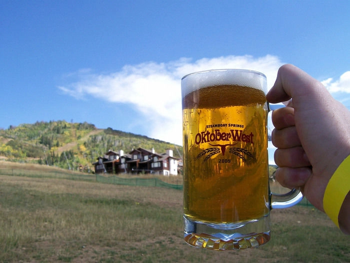 青空とログハウスを背景にビールジョッキを持つ手