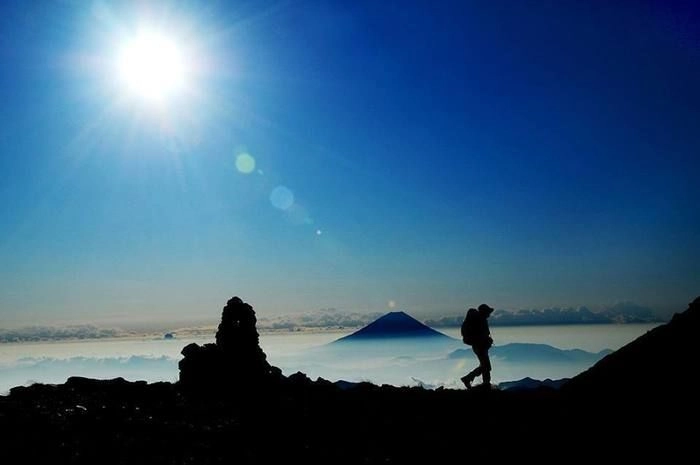 山頂付近で雲を見下ろしながら登山する人