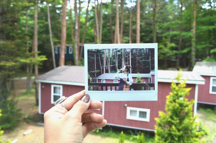 コテージをバックに撮った写真を、そのコテージに重ねて片手に持ち撮ったフォトインフォト