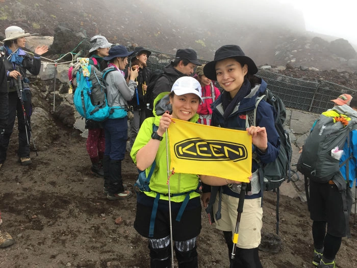 KEENの旗を持って撮影をする登山参加者の女性