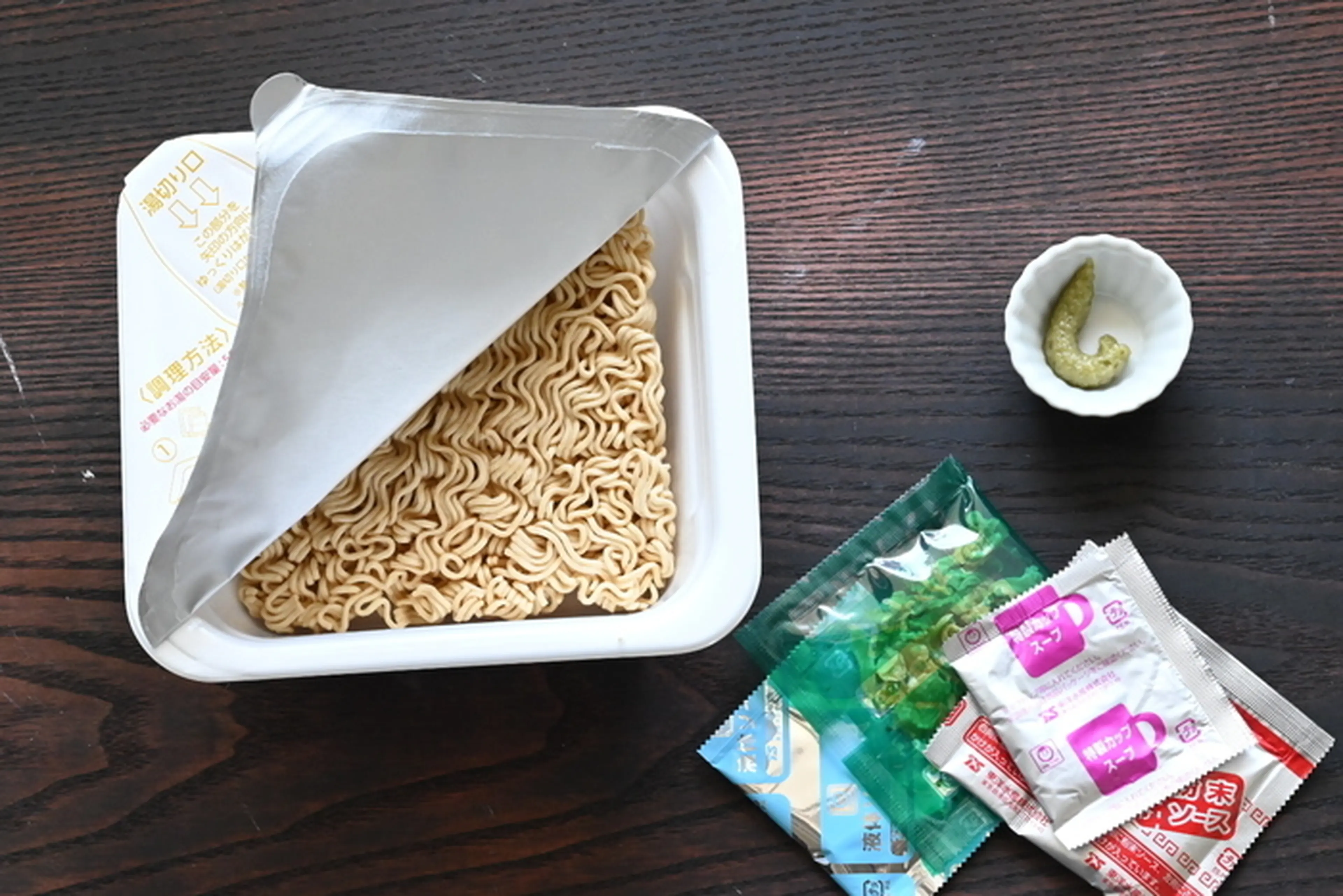 テーブルの上に置かれたカップやきそばと練りわさび
